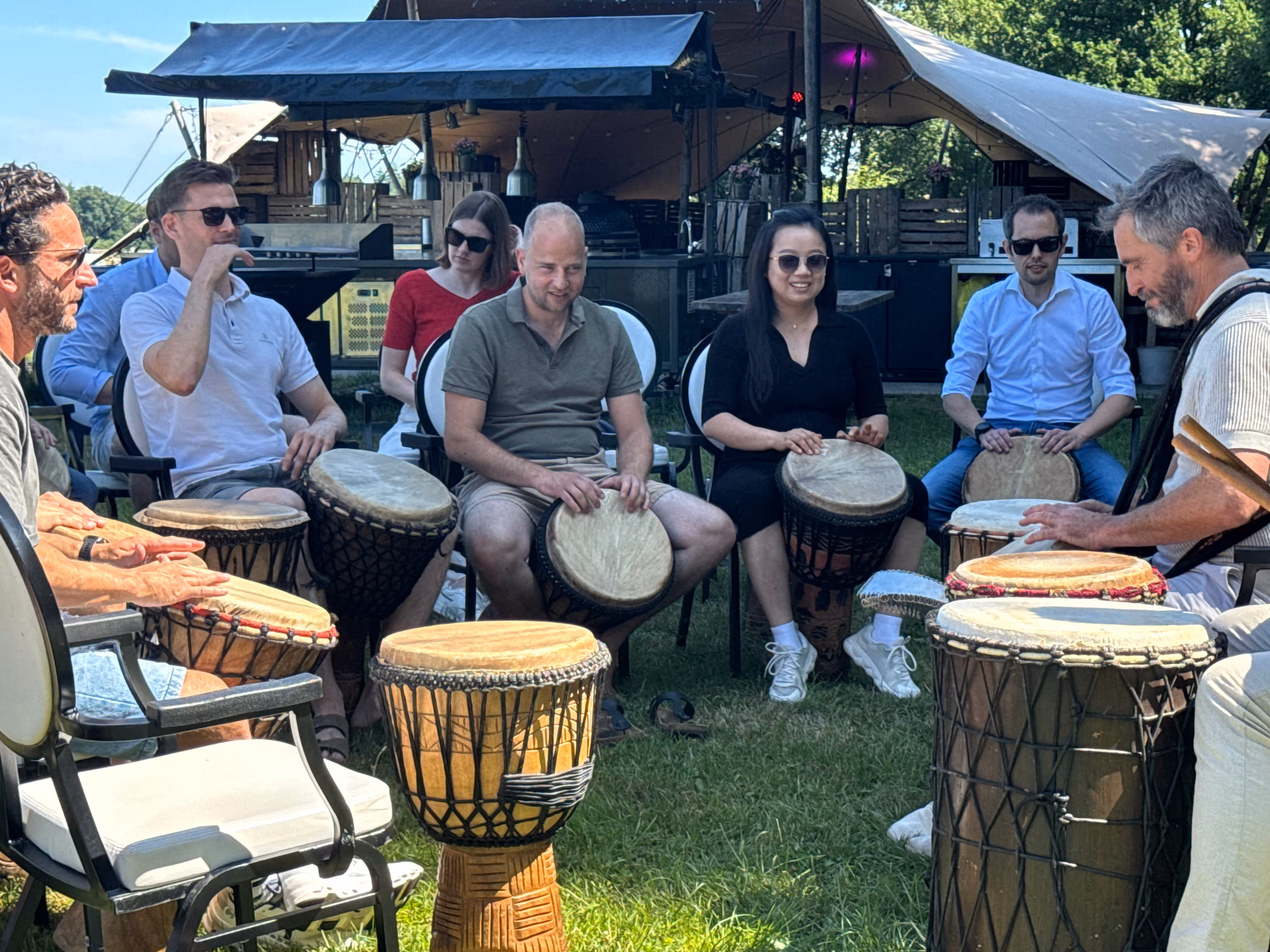 De deelnemers nemen deel aan een percussie workshop op een zomerse dag