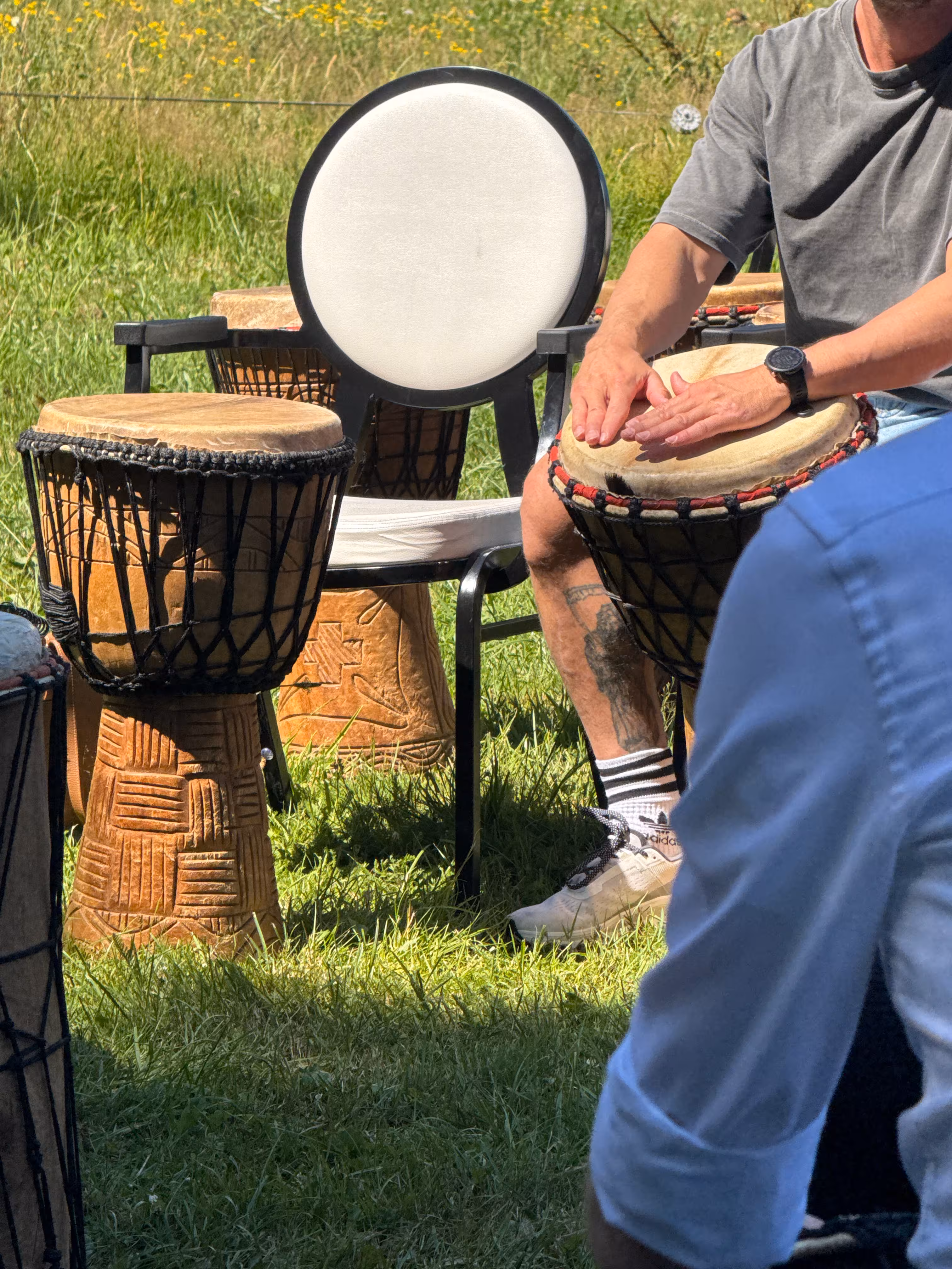 Er wordt op een djembe geslagen tijdens de Percussie workshop die op een grasveld wordt verzorgd