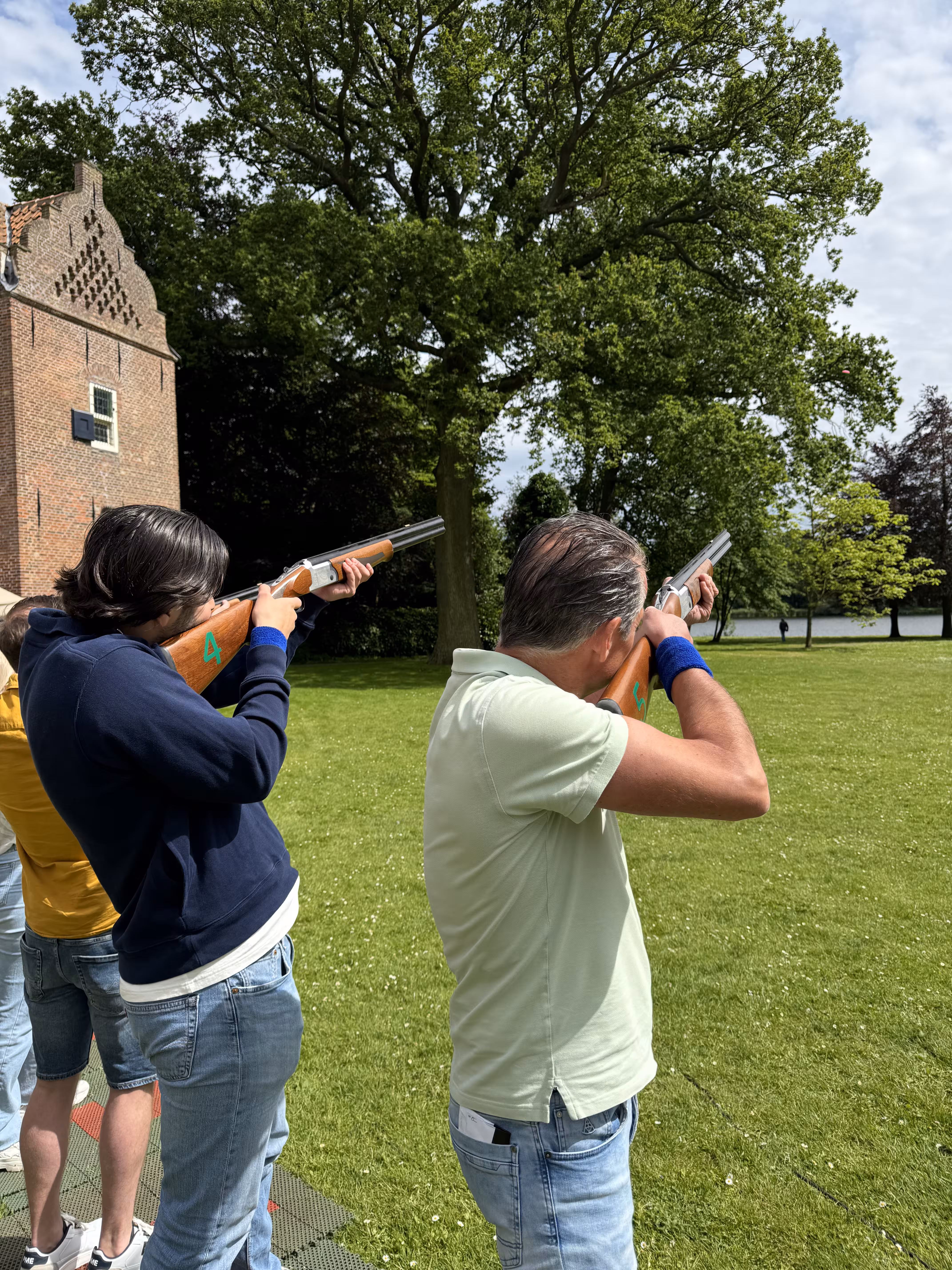 De deelnemers richting met het geweer richting de lasser kleiduif die wordt afgevuurd