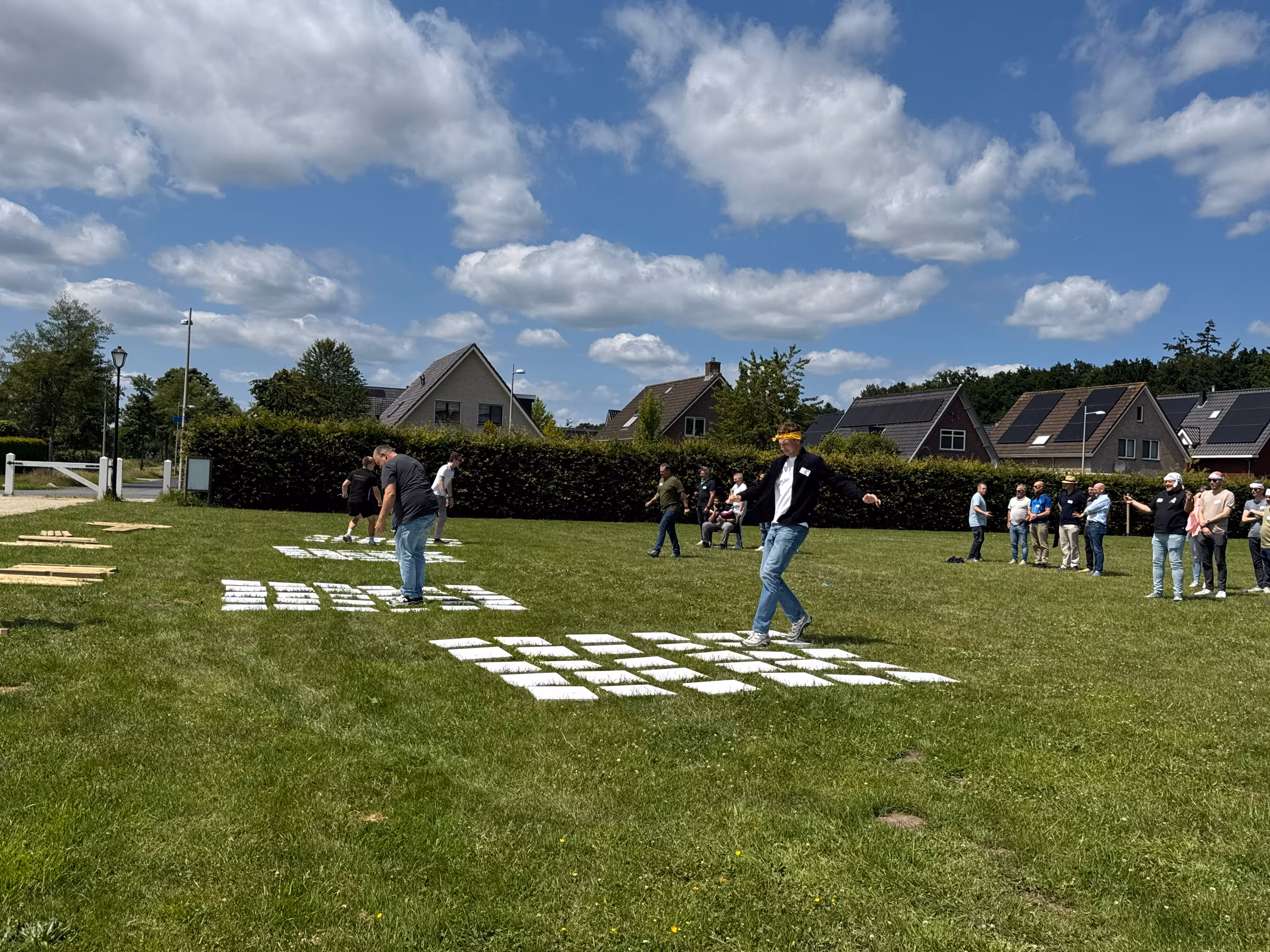 Er is een fictief mijnenveld van witte platen uitgezet op een grasveld tijdens de outdoor teamwork