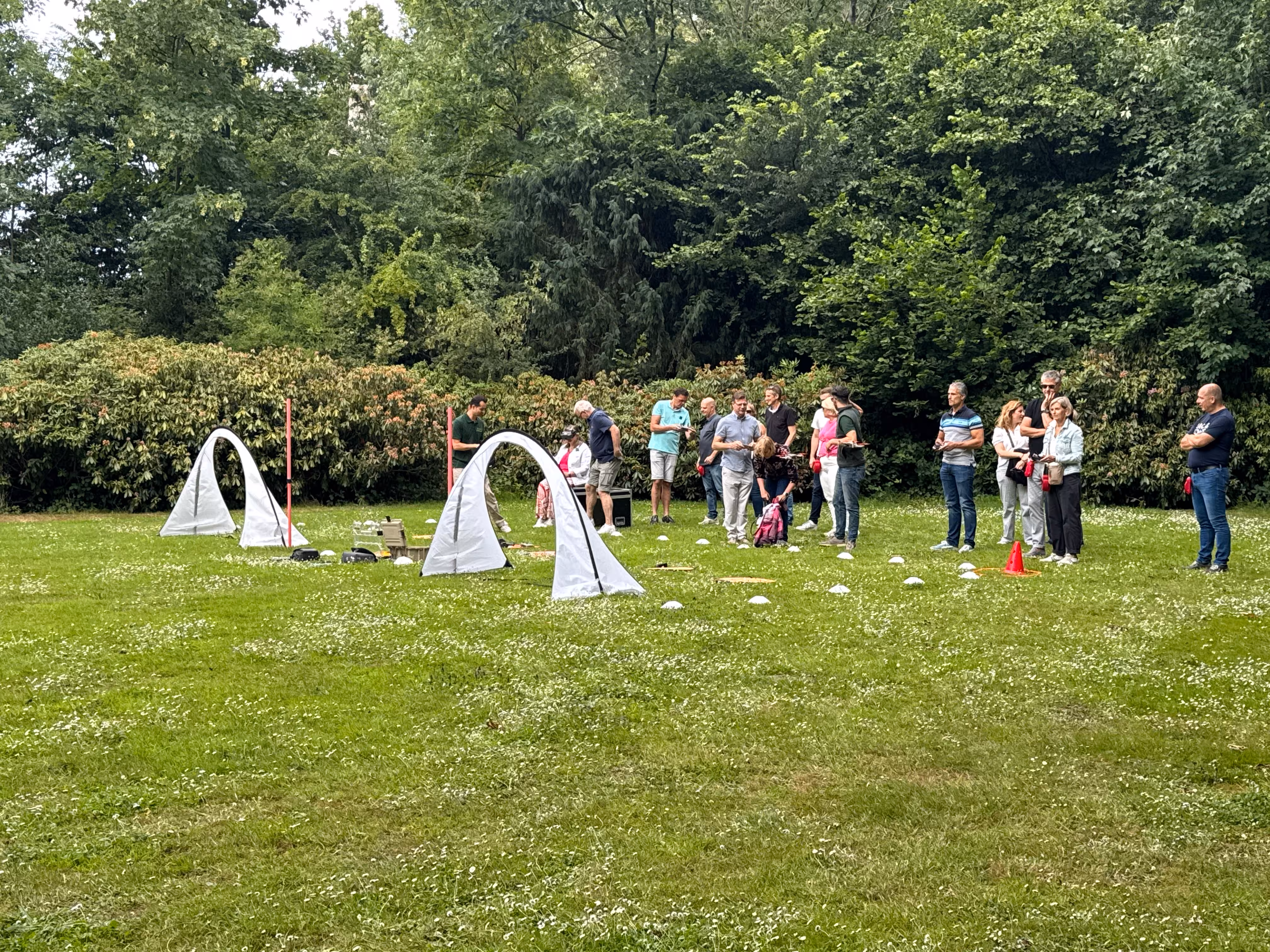 Parcours op een grasveld met witte pionnen en witte bogen voor een drone-workshop