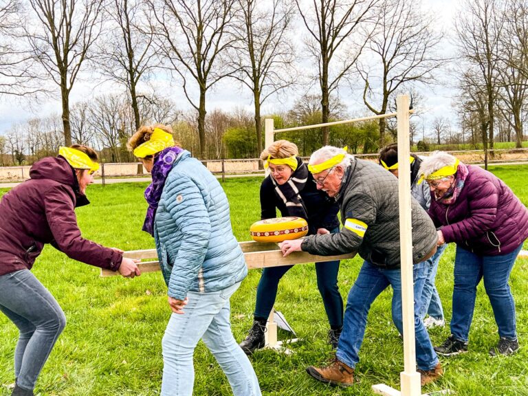 Groep mensen vervoert een kaas op planken onder hindernissen tijdens Alleskunner Teambuilding door BuitenEvents