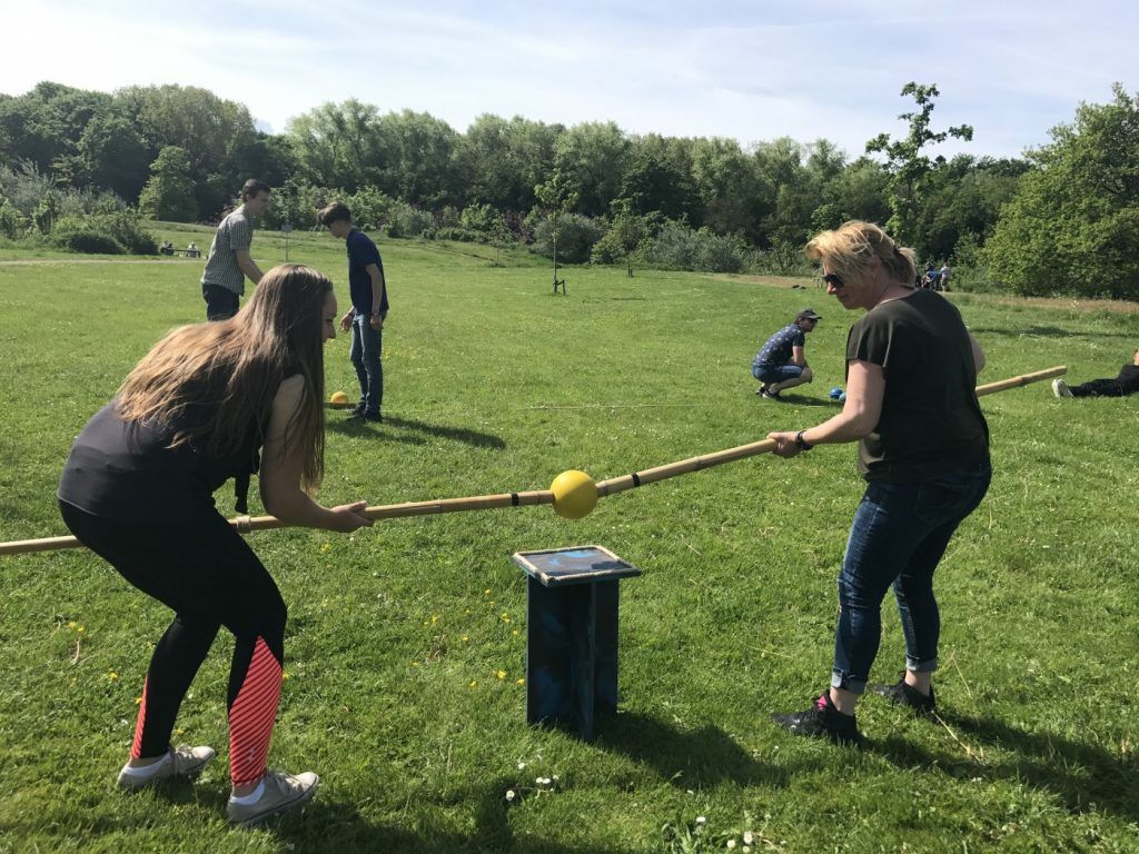 Twee mensen klemmen bal tussen twee stokken tijdens Alleskunner Teambuilding door BuitenEvents