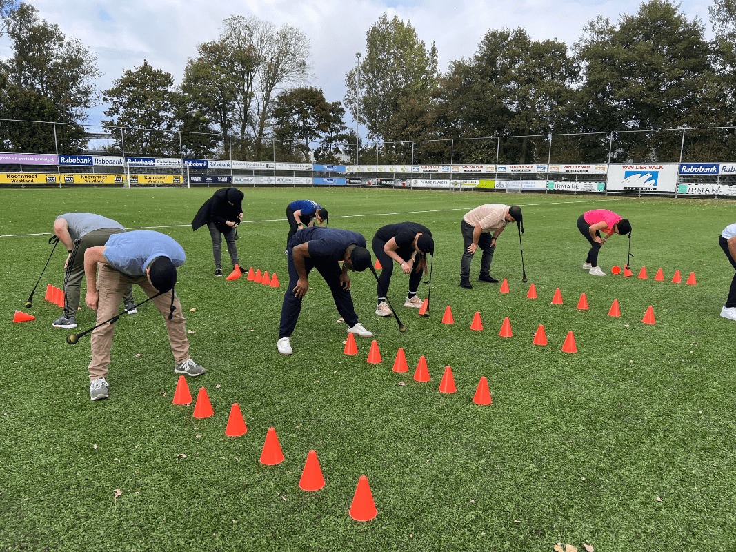 Groep mensen buiten in het veld doet een opdracht met pionnen tijdens de Alleskunner Teambuilding door BuitenEvents
