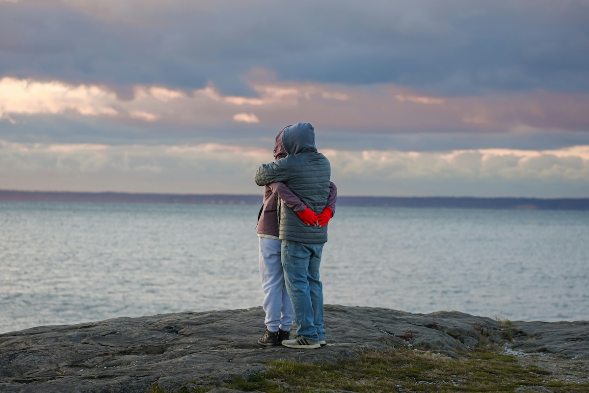 A couple hugging on the rocks overlooking the Atlantic Ocean on Cape Cod.