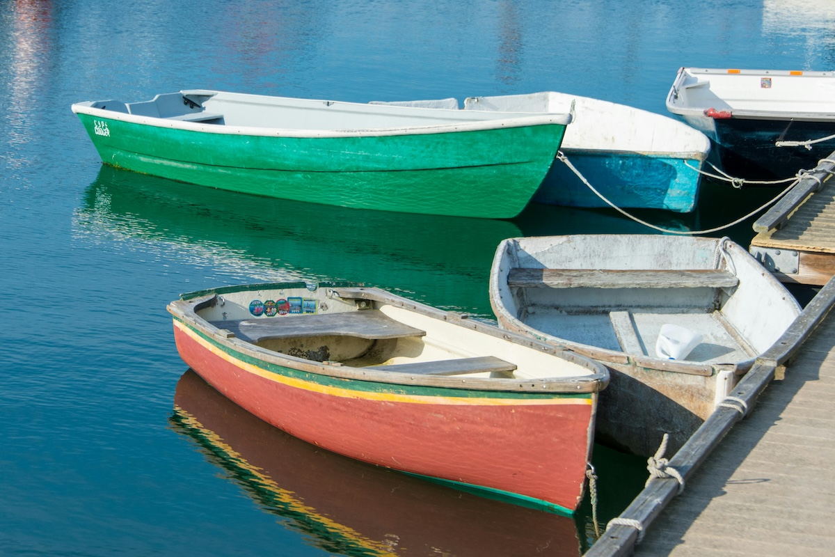 Dockside, several rowboats are tied to a dock, ready to go oot on Pleasant Bay in Orleans on Cape Cod, MA.