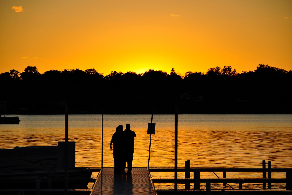 A couple embraces on a pier during a stunning sunset over Pleasant Bay in Orleans MA.