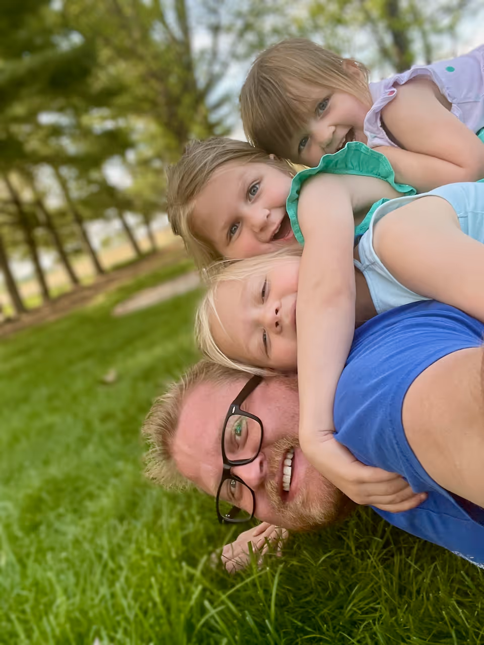 Adam and girls laugh and roll in the grass