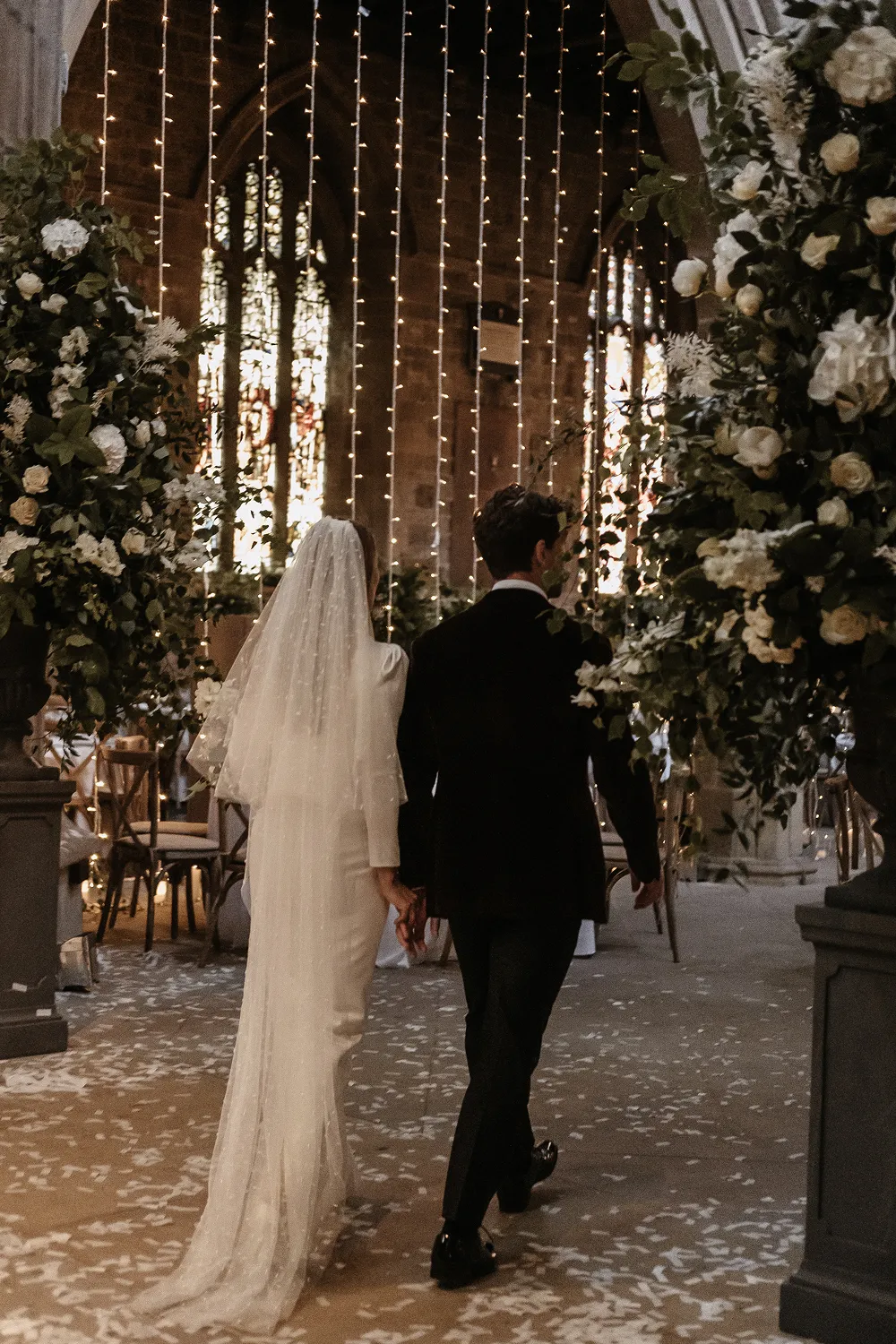 bride and groom walking into reception with tall flower urns either side