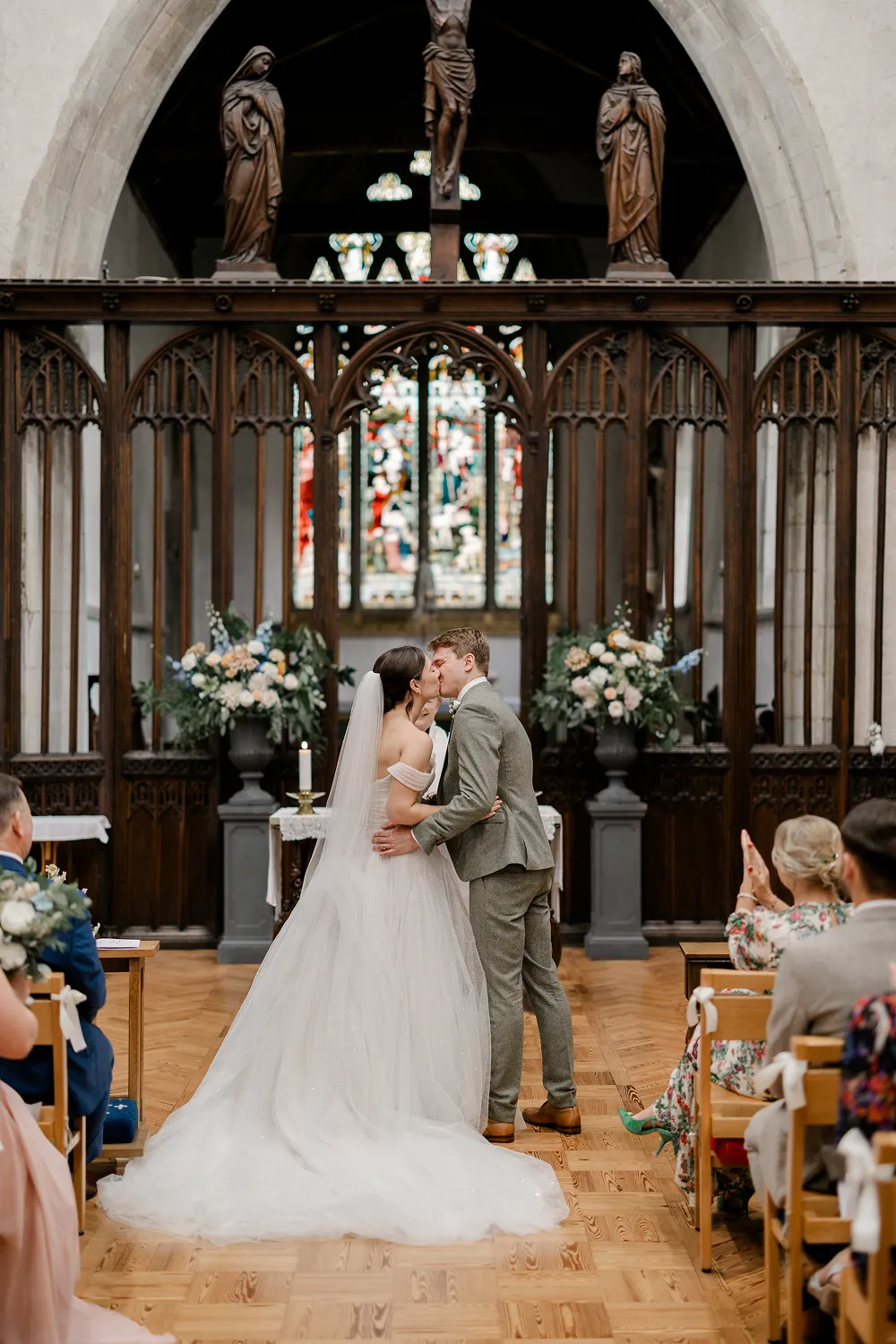 bride and groom kissing with floral displays behind