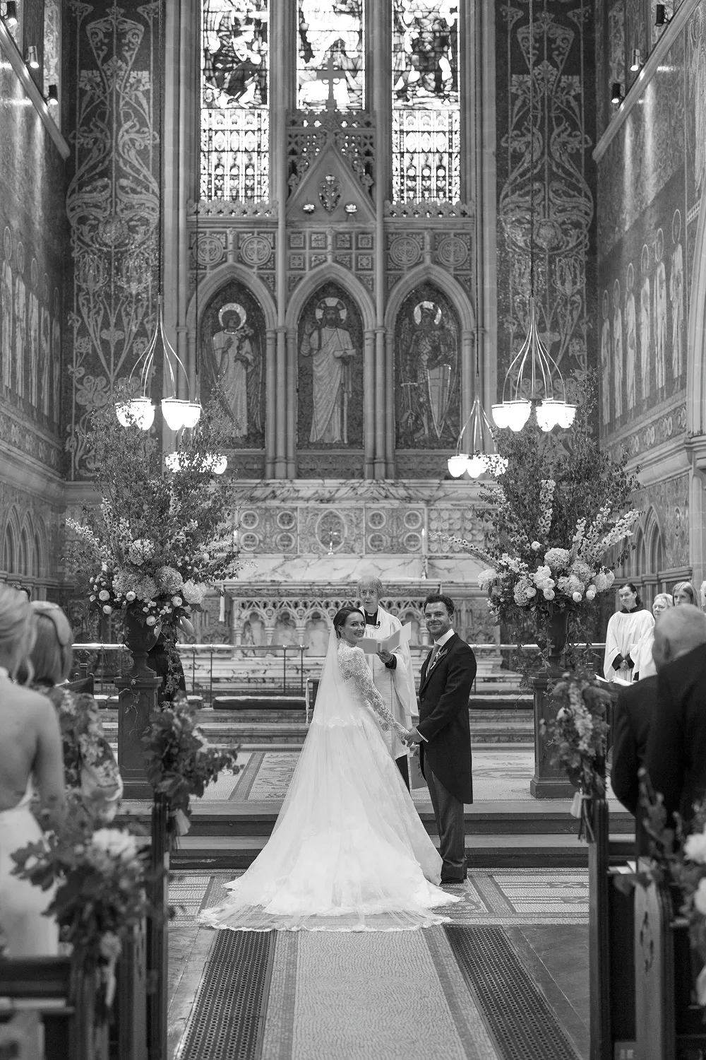bride and groom at alter with large flower displays behind them