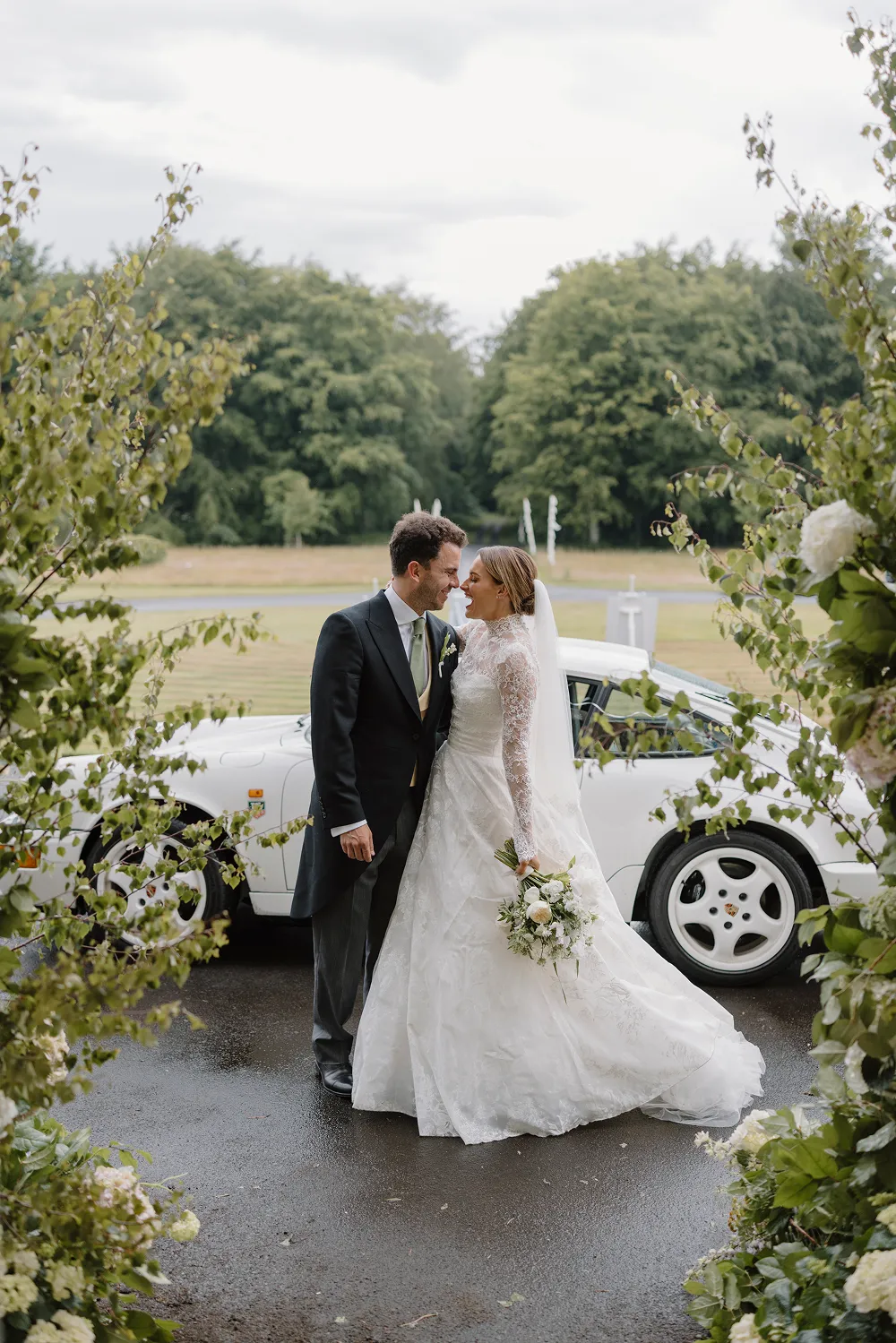 bride and groom outside church with white retro car in the background
