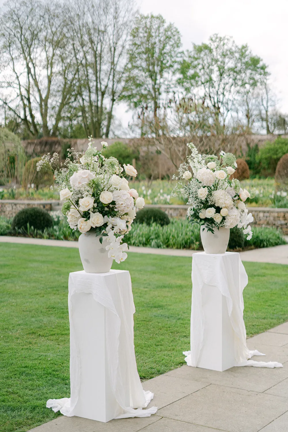 white flower urns on pedestals at wedding