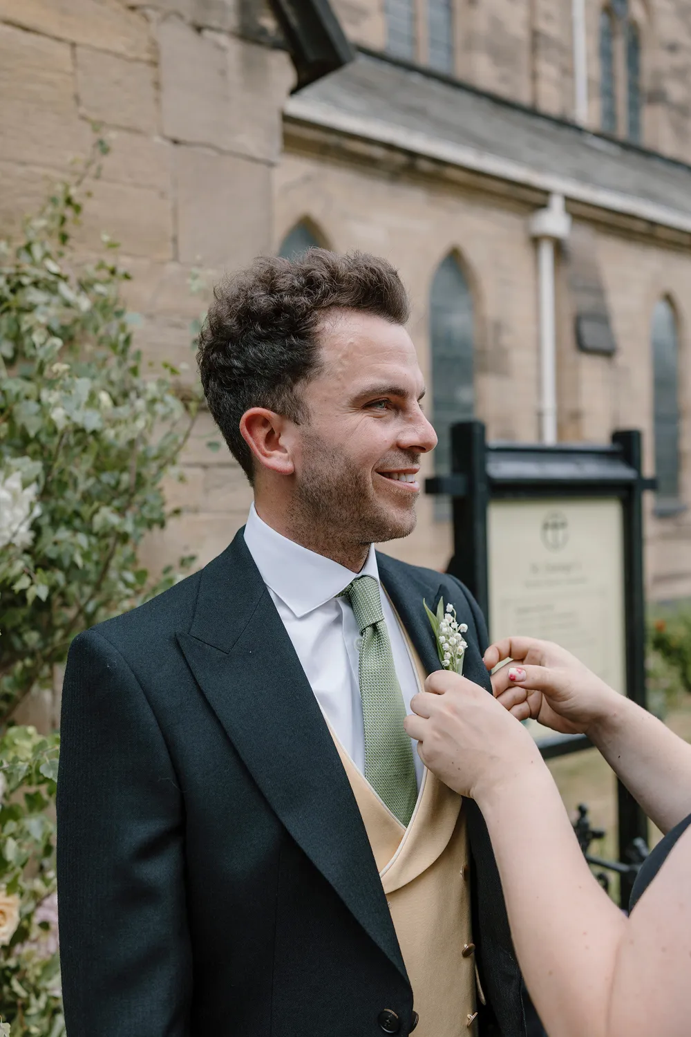 buttonhole being fixed onto groom's jacket
