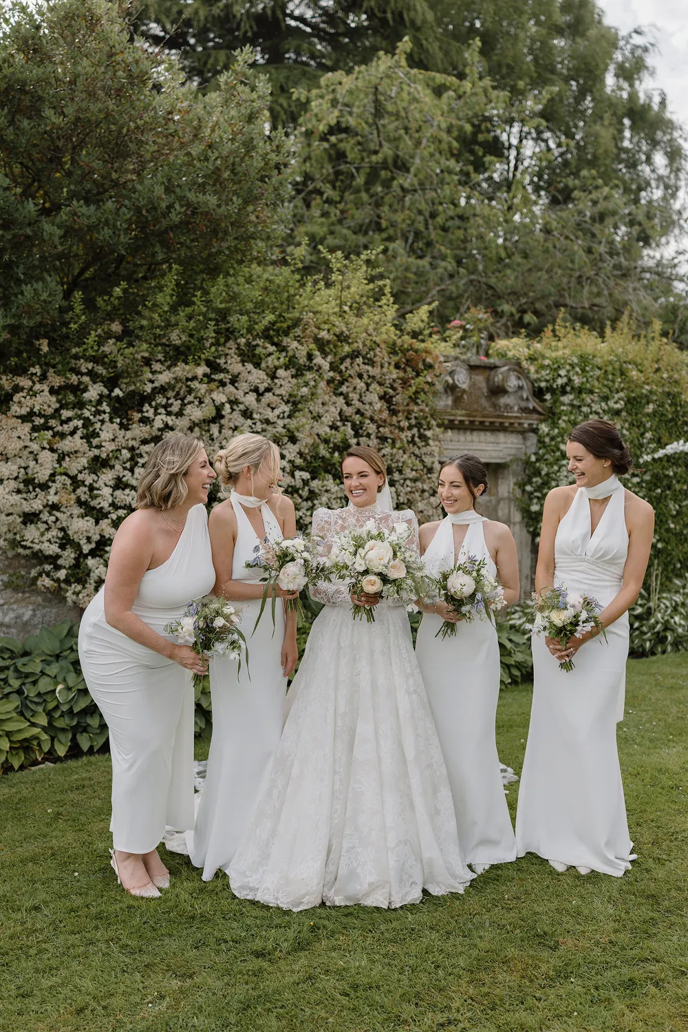 bridesmaids and bride all laughing with matching floral bouquets
