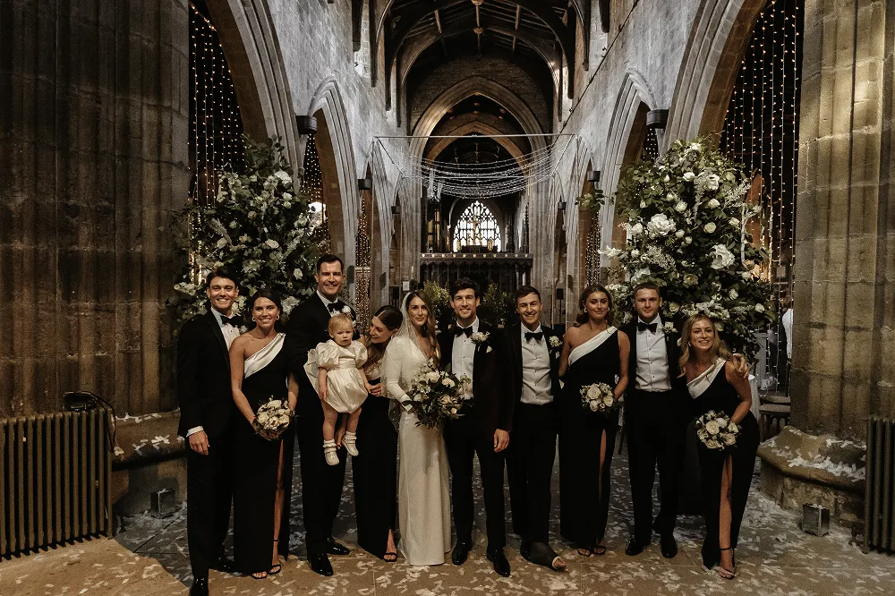 wedding party smiling with matching bouquets and flowers behind