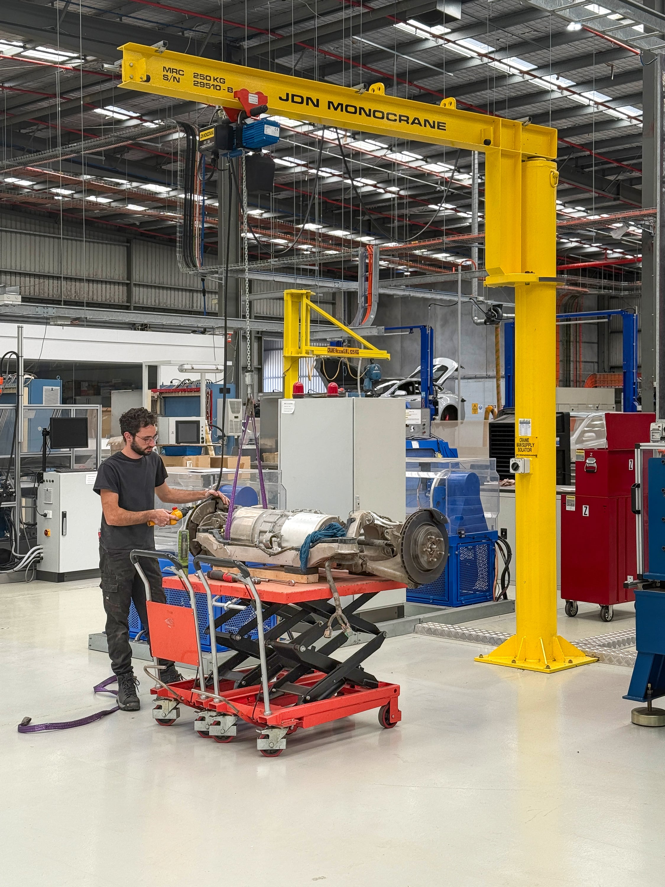 Jaunt technician working on Tesla Large Drive Unit under jib crane in workshop