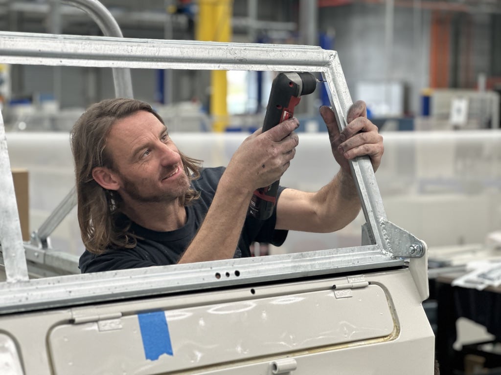Technician fitting windscreen frame with safari windows