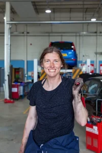 Eine Mechanikerin lacht in die Kamera