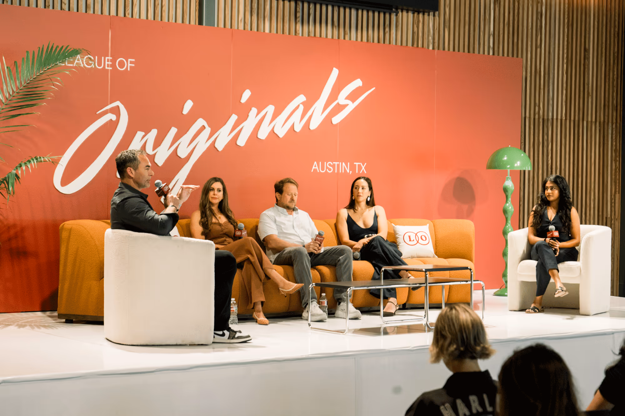 Panel discussion with five people seated on stage against a red backdrop reading 'League of Originals Austin, TX'.