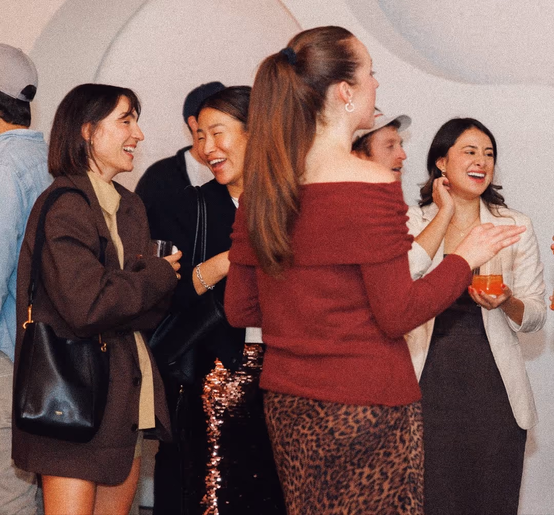 Group of young adults laughing and talking at a social gathering indoors.
