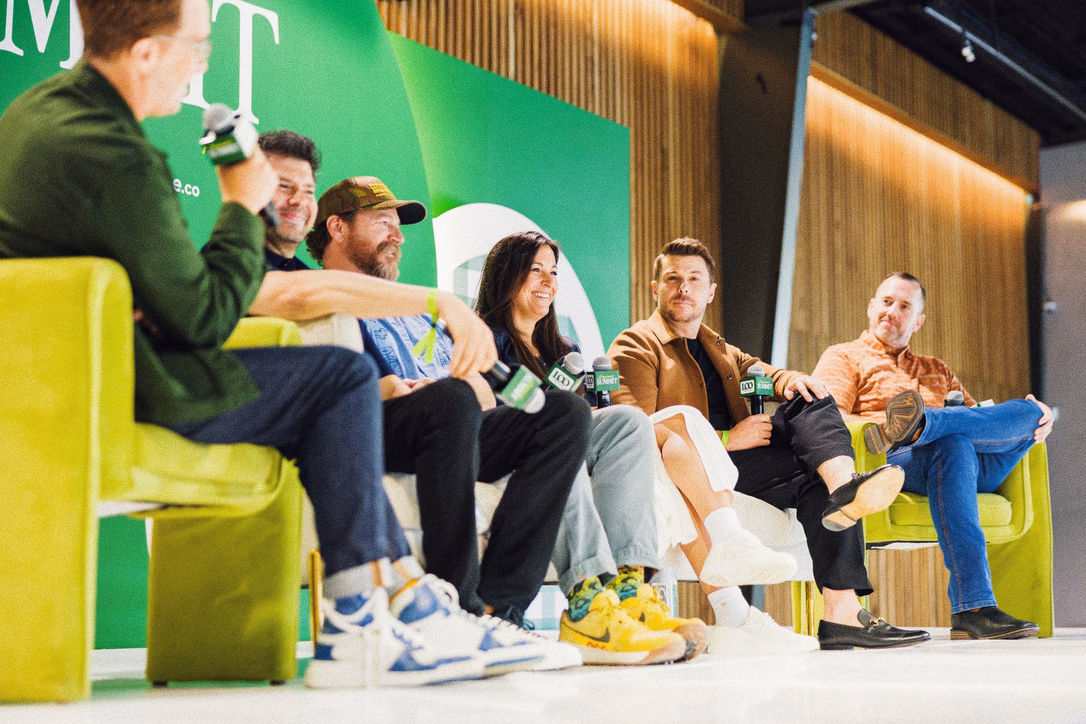 Five people seated on stage chairs during a panel discussion with microphones in hand.