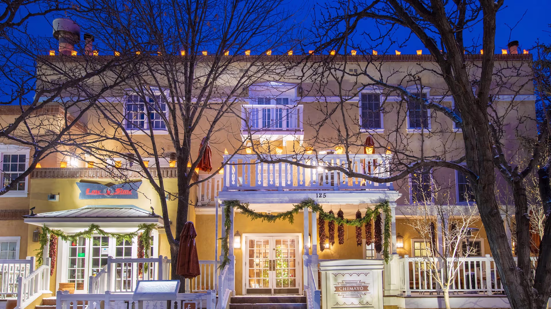 Hotel Chimayo exterior at night with farolitos and garland