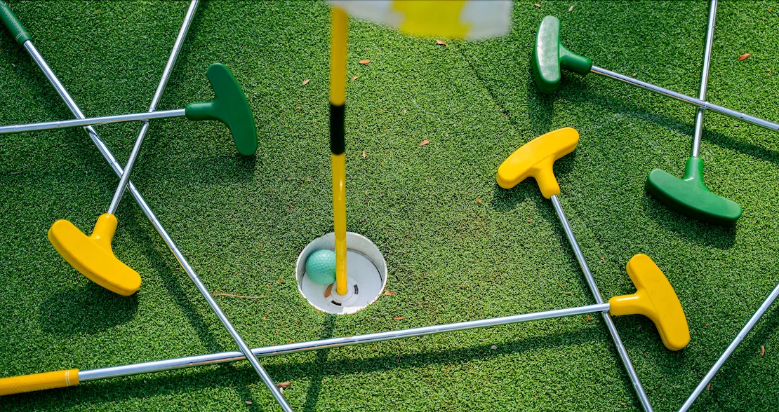 A group of people playing mini-golf to raise money for a baseball team