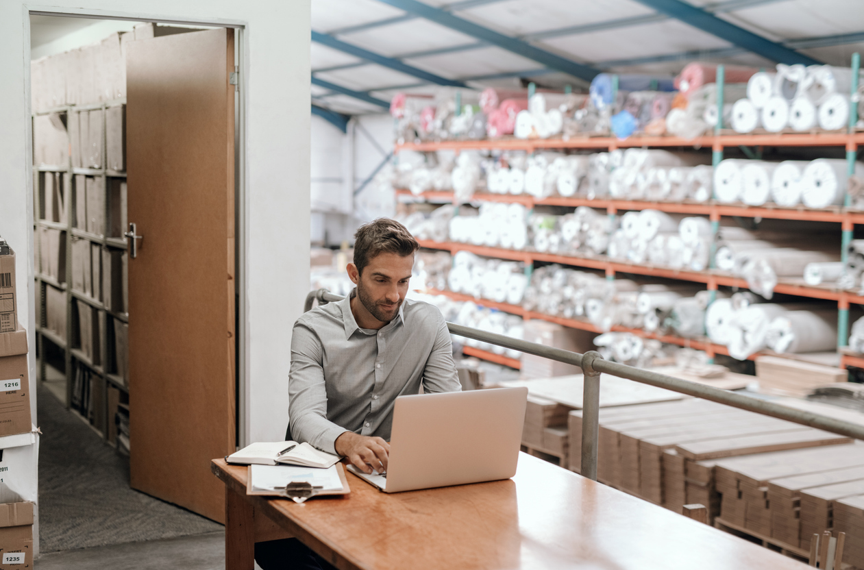 a man managing his ecommerce business on his computer at his warehouse