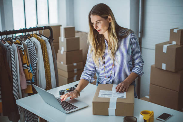 woman in room with boxes shipping off orders on her computer