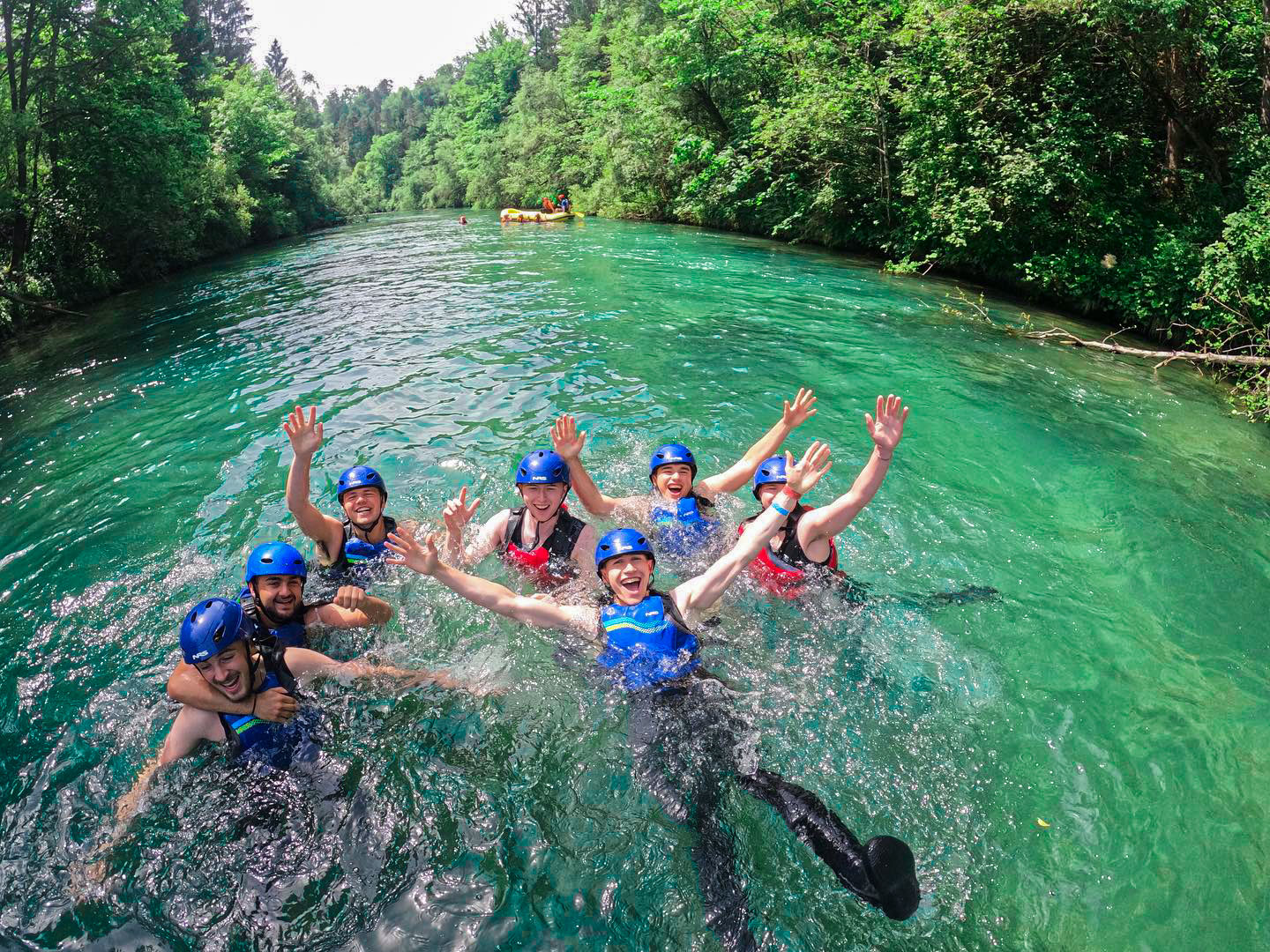 group of rafters all wave in the crystal clear waters of the sava dolinka river