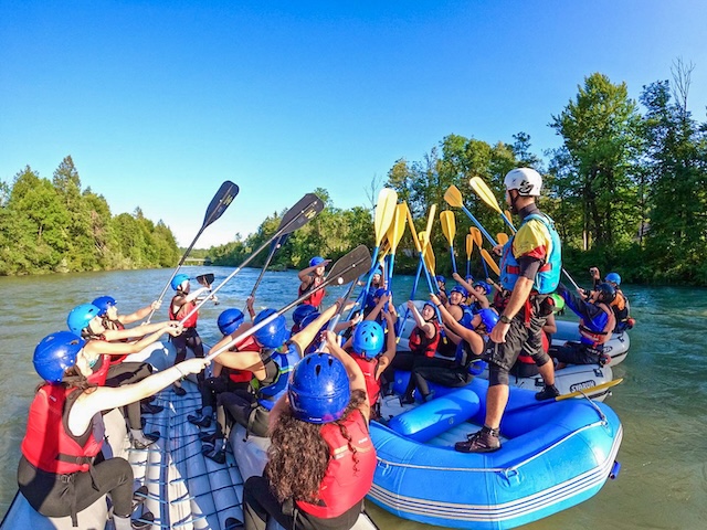 group of rafts put their paddles together as a team while the guide stands u at the back of the raft