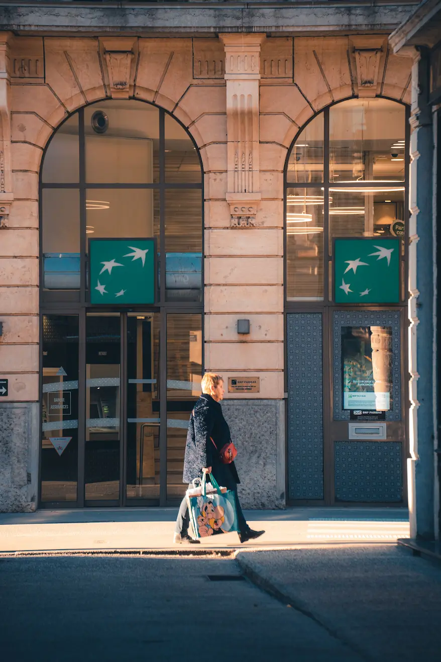 Femme marchant devant une succurale de la BNP Paribas