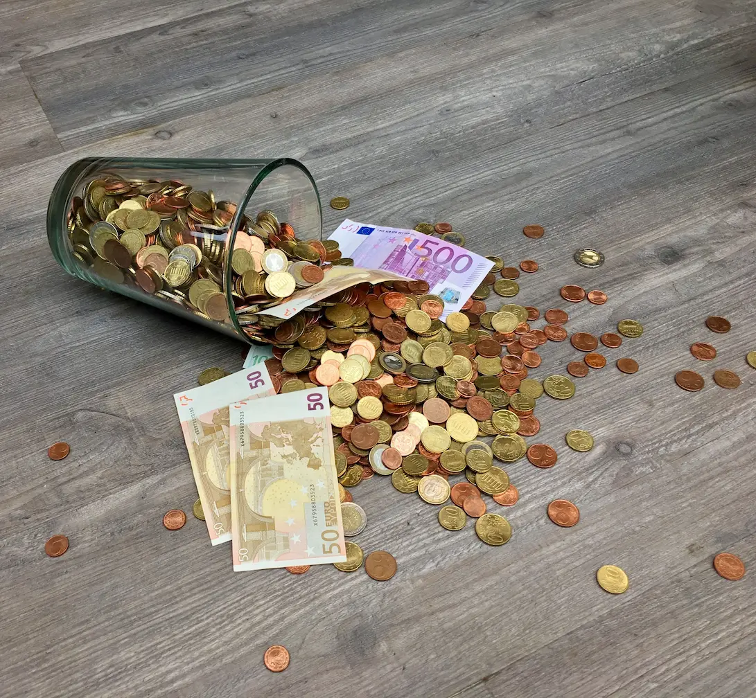 Verre tombé, rempli de pièces et billets d'euros