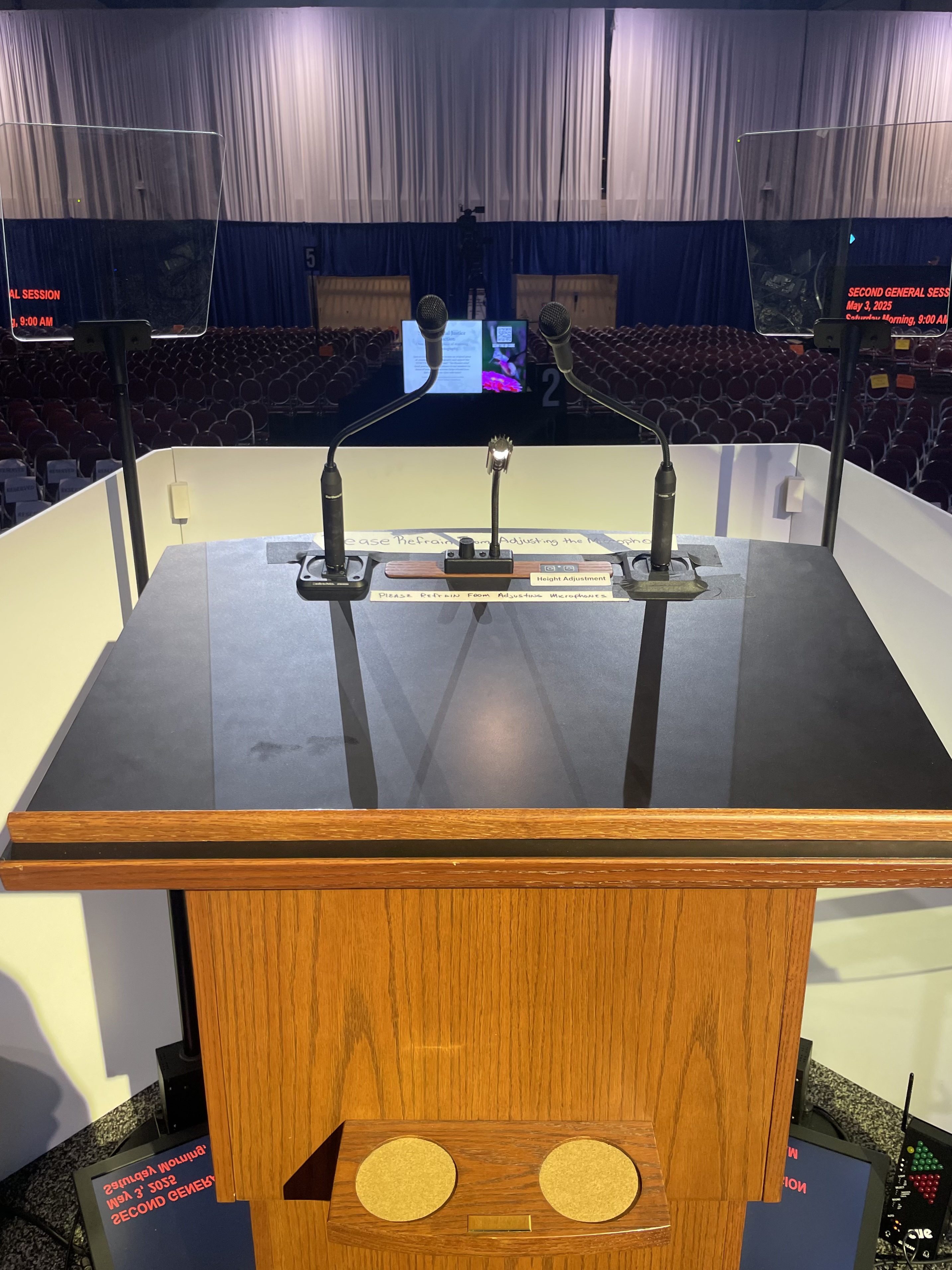 Podium framed by dual presidential teleprompter glass panels at a live event