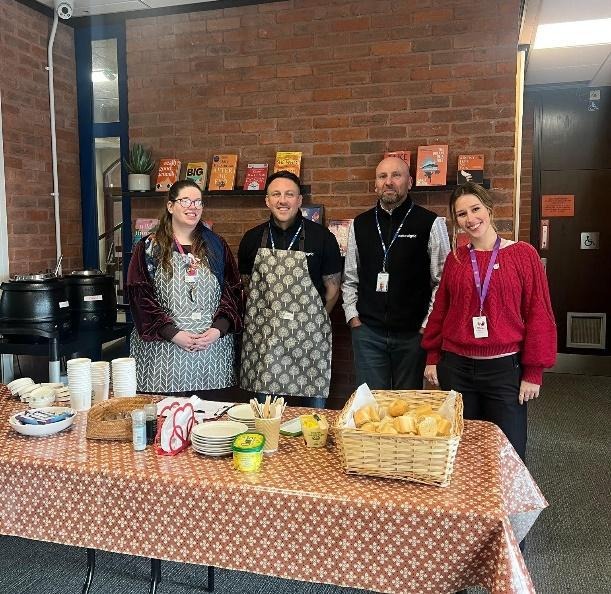 A group of people standing in front of a tableAI-generated content may be incorrect.