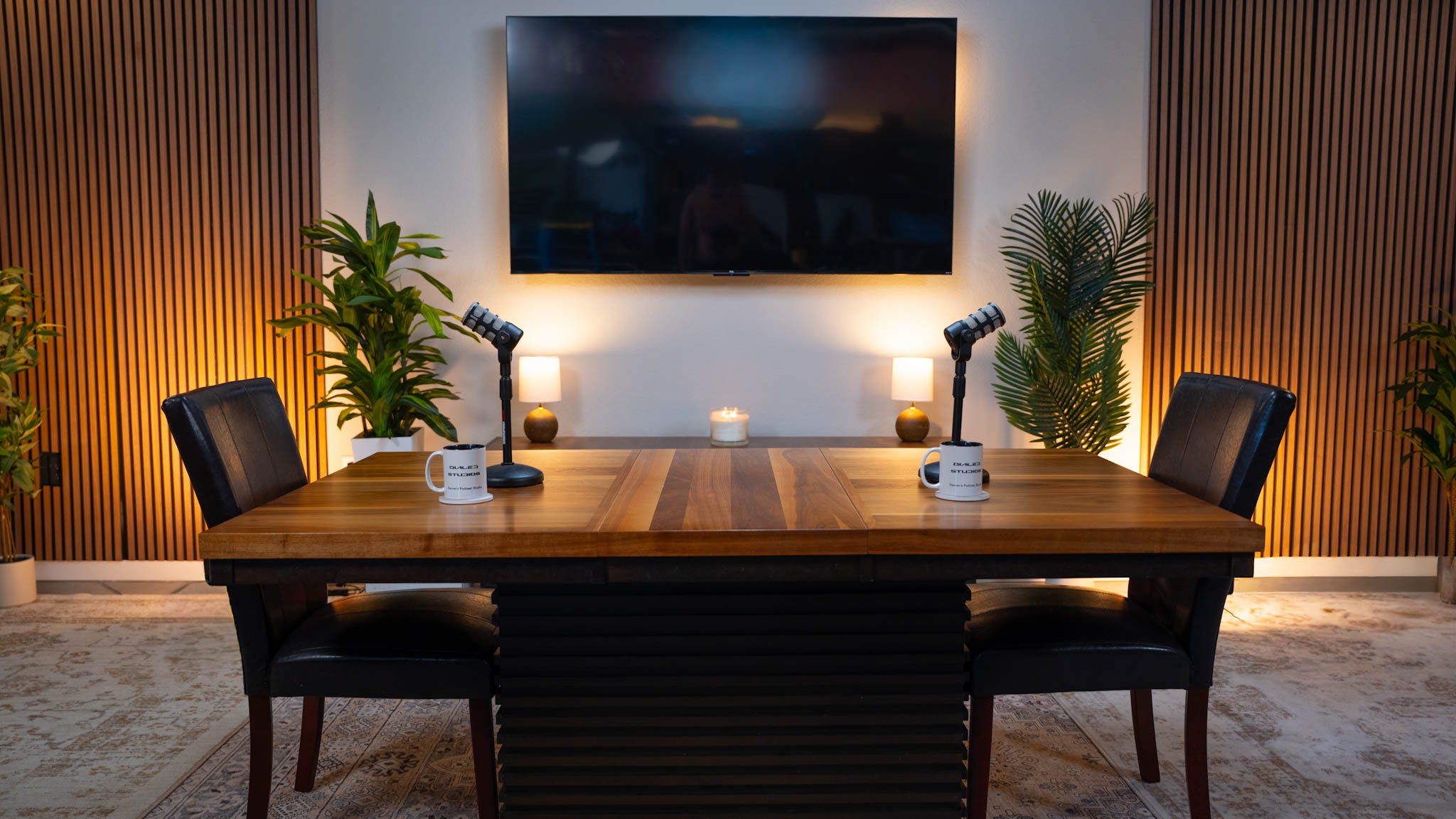 The lit podcast set at Dialed Studios in Denver, with a wood table, microphones and a wall screen