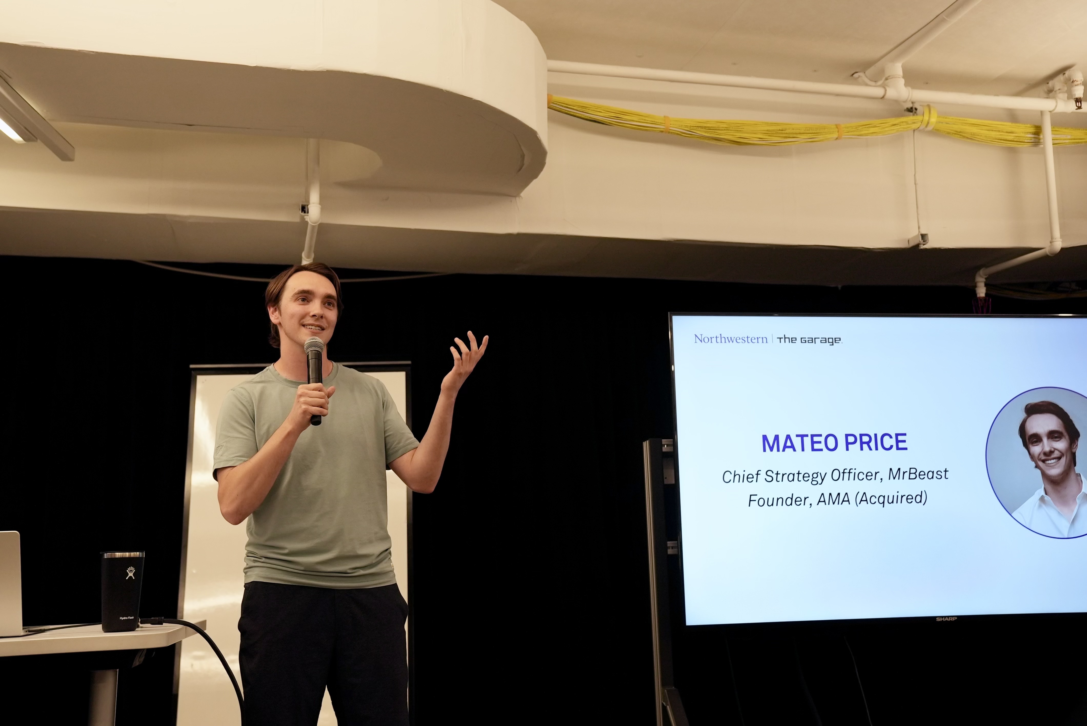 Mateo Price standing in front of a screen holding a microphone.