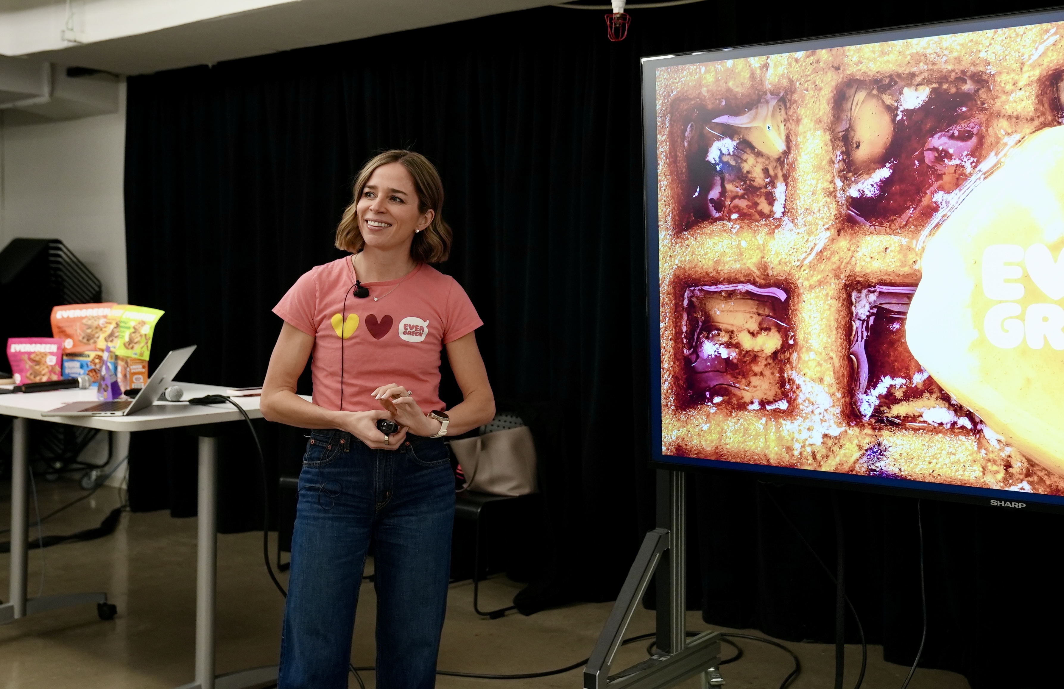 Emily stands in front of a screen with a closeup picture of a waffle
