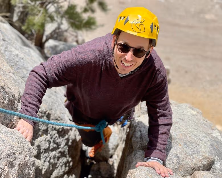 Photo of smiling man rock climbing