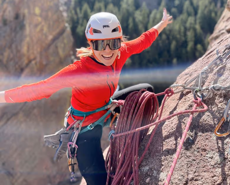 Photo of happy woman finishing a rock climb in Boulder