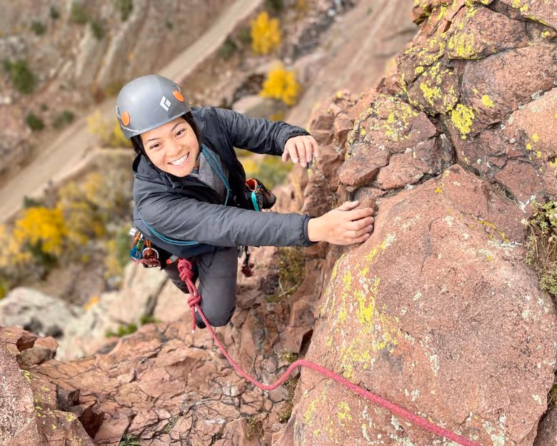 Photo of woman smiling while rock climbing in Boulder