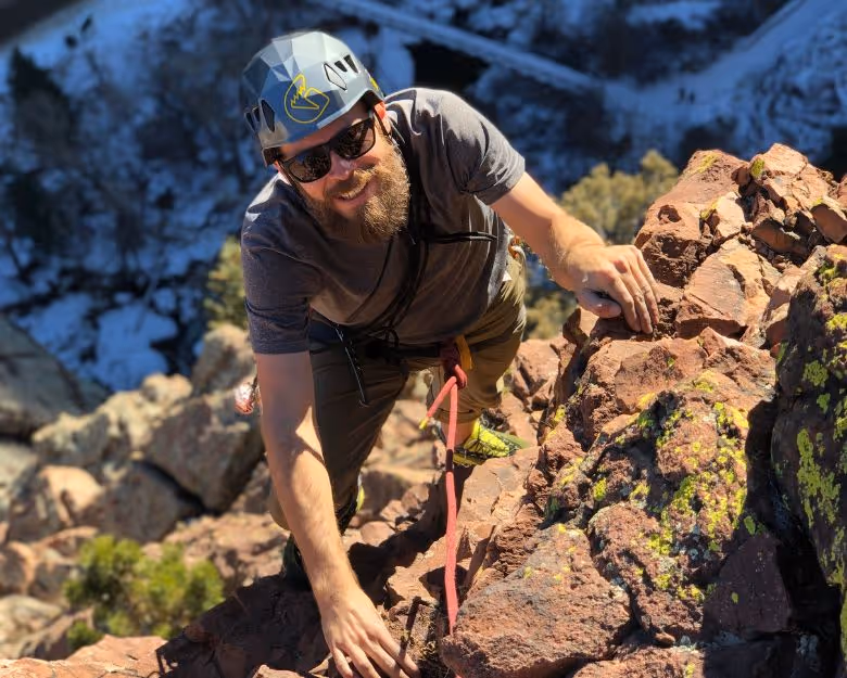 Photo of man smiling while rock climbing in Boulder