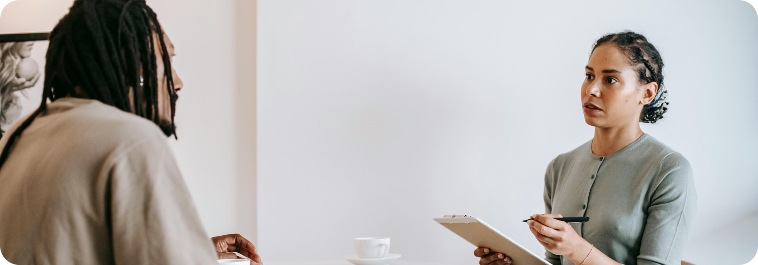 A serious-faced woman with a clipboard talking to a man
