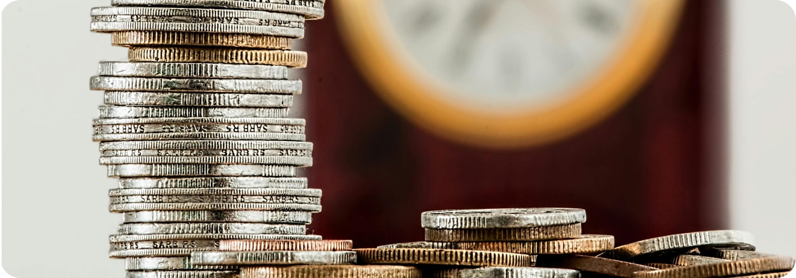 A stack of quarters in front of a clock