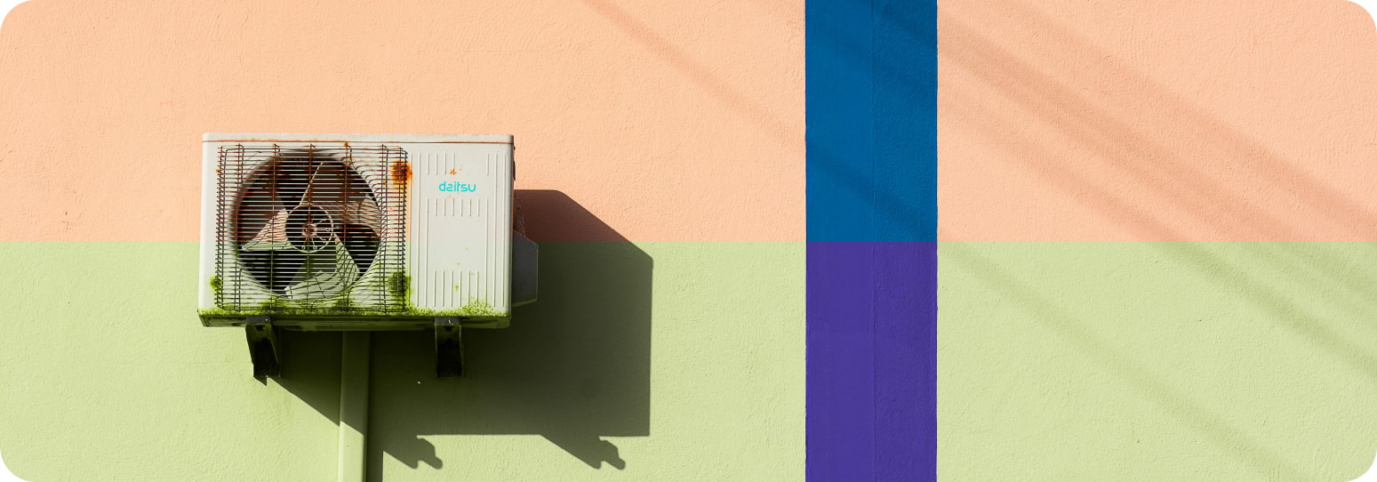 On old HVAC machine outside on a pink will with a blue line