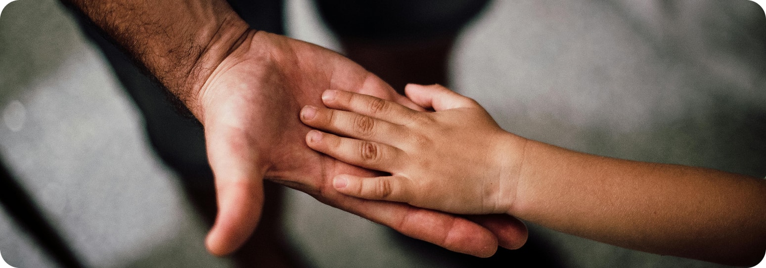 A small child's hand in a larger, parent's hand