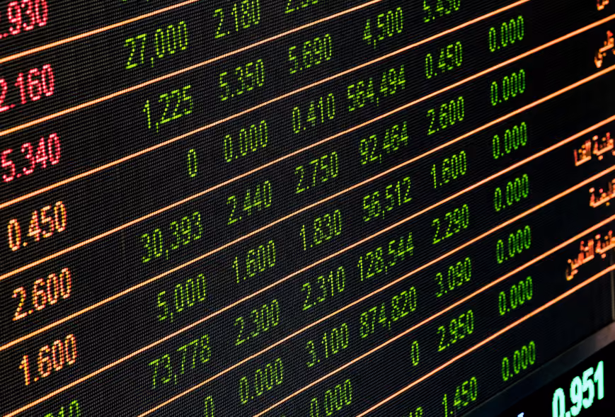 Close-up of a glowing stock exchange ticker with red, green, and orange numbers on a dark LED board