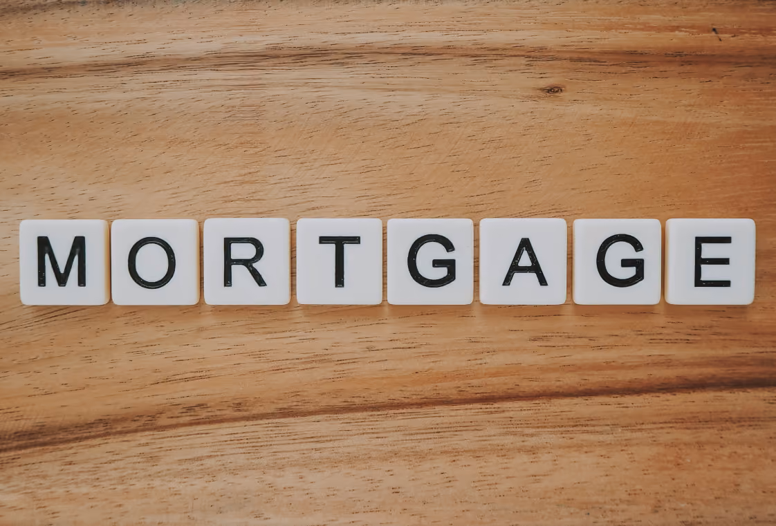 The word MORTGAGE spelled in white letter tiles on a light wood surface