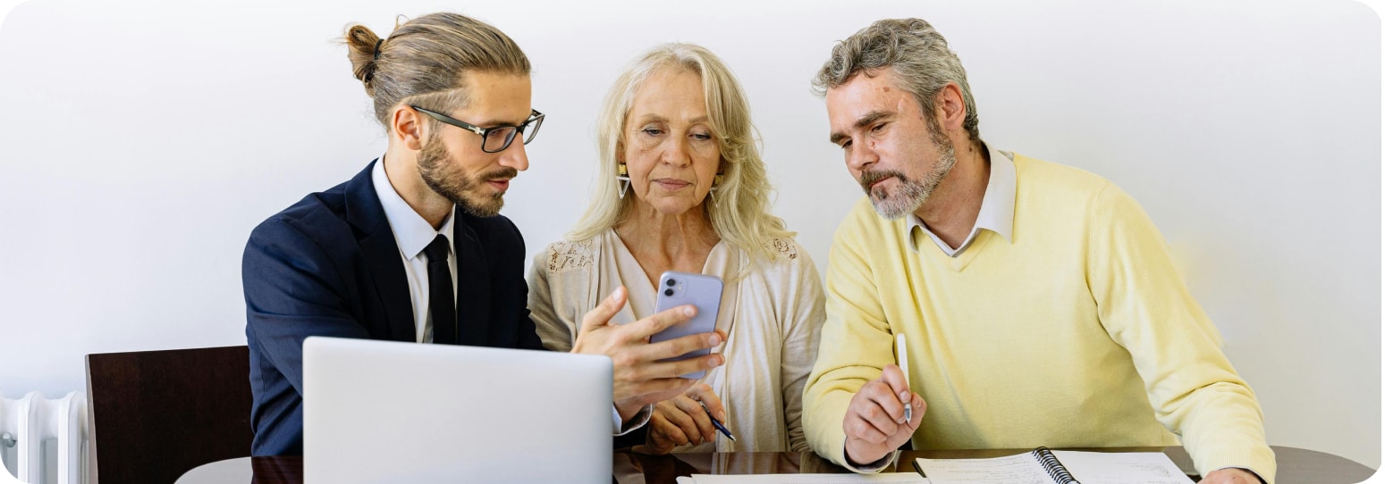 Man in suite showing a couple his phone